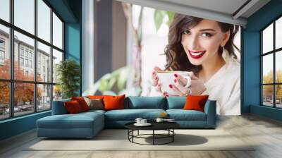 Young girl drinking coffee in a trendy cafe Wall mural