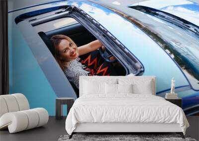 Young woman driving with sunroof open Wall mural