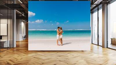 Pregnant woman with husband expecting baby at tropical beach with blue ocean Wall mural