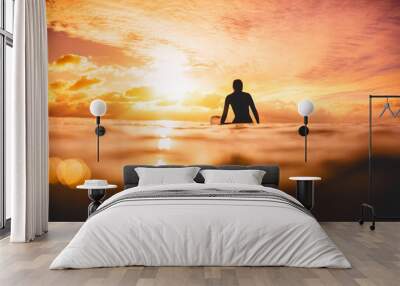 surfer woman in ocean at sunset or sunrise. winter surfing in ocean Wall mural