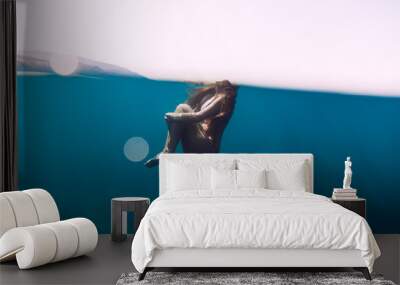 Woman floating in blue ocean. Underwater view Wall mural