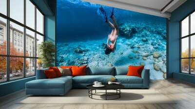 Woman free diver in bikini swim to deep in the tropical blue ocean Wall mural