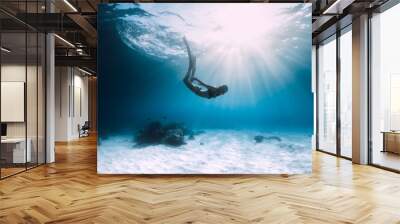 Woman freediver dive over sandy sea with fins. Freediving in blue ocean Wall mural