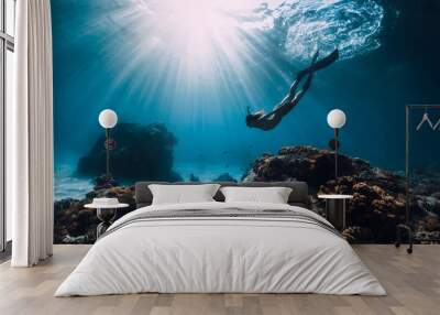 Woman freediver with fins underwater. Freediving and beautiful light in ocean Wall mural