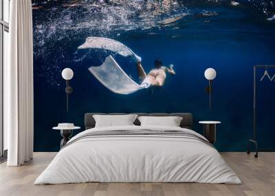 Woman with white freediving fins swim in surface underwater in ocean Wall mural