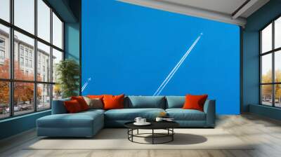 Airplane with white condensation tracks. Jet plane on clear blue sky with vapor trail. Travel by airplane concept. Trails of exhaust gas from airplane engine. Aircraft with white stripes. Wall mural