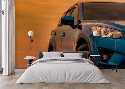 Blue compact SUV car with sport and modern design parked on concrete road by the sea at sunset in the evening. Hybrid and electric car technology concept. Car parking space. Automotive industry. Wall mural