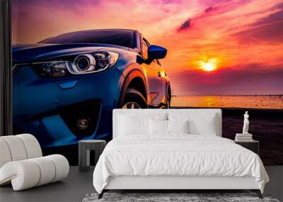 Blue compact SUV car with sport and modern design parked on concrete road by the sea at sunset. Environmentally friendly technology. Business success concept. Wall mural