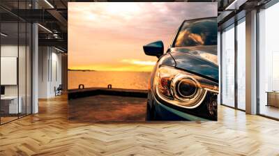 Blue compact SUV car with sport and modern design parked on concrete road by the sea at sunset. Environmentally friendly technology. Business success concept. Wall mural