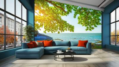 Blue sport SUV car parked by the tropical sea under umbrella tree. Summer vacation at the beach. Summer travel by car. Road trip. Automotive industry. Hybrid and electric car concept. Summer vibes. Wall mural