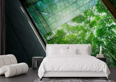 Eco-friendly building in modern city. Sustainable glass office building with trees for reducing carbon dioxide. Office building with green environment. Corporate building reduce CO2. Net zero emission Wall mural