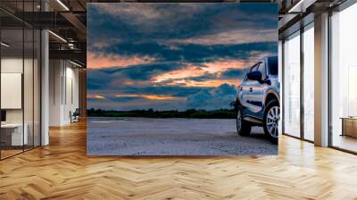 Luxury blue SUV car parked on land beside tropical forest with beautiful sunrise sky. New car with sport and modern design. Car drive for adventure road trip. Nature landscape. Automotive industry. Wall mural