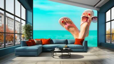 Upside woman feet and red pedicure wearing pink sandals, sunglasses at seaside. Funny and happy fashion young woman relax on vacation. Chill out girl at beach. Creative for tour agent. Weekend travel. Wall mural