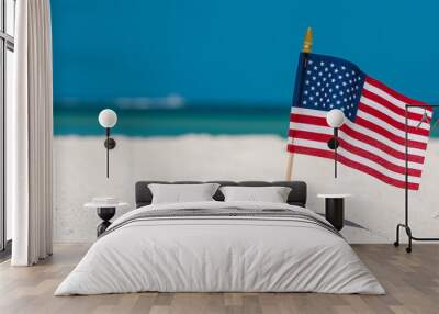 American Flag on the Beach. 4th of July Independence Day. US starry striped patriotic symbol. United States Holidays. Summer vacations. Ocean sand. Bright sunny day and blue color of sea salt water.  Wall mural