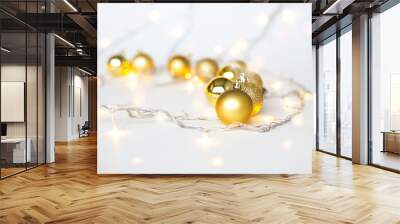 Christmas lights in warm yellow white on string and gold xmas balls over light background with copy space for text, logo decoration on Xmas eve celebration, special holidays, new year event concept Wall mural