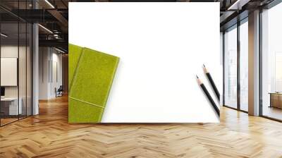 Recycled paper notebook in green colour and two black pencils over white background with copy space for text insertion, green concept environment for saving earth Wall mural