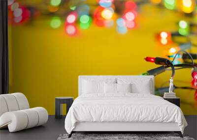 Xmas light bulbs on string in multi colours; blue, yellow, green, pink & red on gold yellow background with copy space & bokeh (blurry lights) for Christmas, new year celebration (pine tree ornament) Wall mural