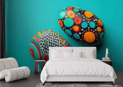 Two stones with elaborate, colorful designs lie against a turquoise background, featuring intricate and vibrant patterns. Wall mural