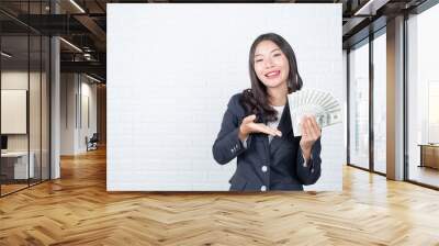 A young businesswoman holds a dollar note on a white brick wall background. Wall mural