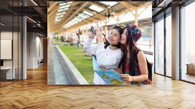 Two women are holding the map while waiting for the train. Tourism concept Wall mural