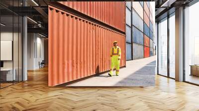 Asian man engineer walking and checking containers at a container yard. Shipping business management and international goods import-export. Concept of logistic operation. Photo with copy space. Wall mural