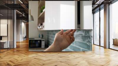 Kitchen interior with modern furniture. The man opens a modern hanging cabinet for a kitchen without door handles Wall mural