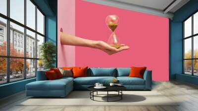 Sandglass on a woman's hand on a duotone background. Wall mural