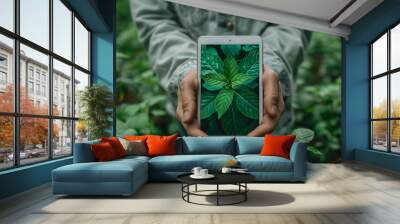 Man hold white tablet show green plants, surrounded by lush greenery in garden setting. Green energy concept, eco friendly gadgets, alternative energy technologies Wall mural