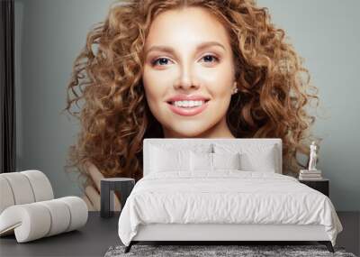 Attractive redhead girl with clear skin and long healthy curly hair. Beautiful female face on gray background Wall mural