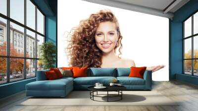 cheerful woman with long curly hair, clear skin and empty open hand isolated on white background Wall mural