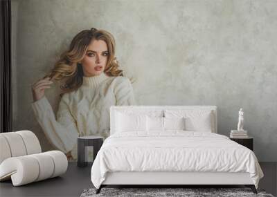 Elegance model woman with make-up and wavy hairstyle wearing white sweater against gray stucco plaster background wall with copy space Wall mural