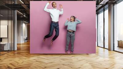 Young jumping people. Young man and woman on bright pink background Wall mural