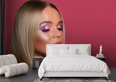 Young pretty model woman with makeup and blonde hair on pink background Wall mural