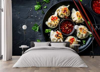 A plate of dumplings with red sauce, sesame seeds and coriander leaves, set against a black natural stone backdrop. Wall mural