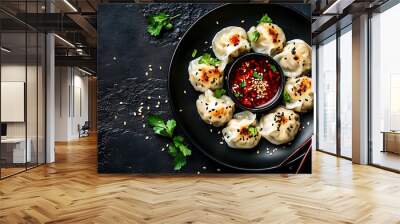 A plate of dumplings with red sauce, sesame seeds and coriander leaves, set against a black natural stone backdrop. Wall mural