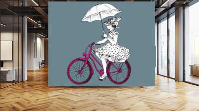 Lady in polka dot dress in hat and high heels with open umbrella riding pink bicycle, hand drawn doodle, sketch black and white outline vector illustration on gray background Wall mural