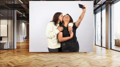 photograph of a female couple taking a selfie on a light studio background. Concept of people and human relationships. Wall mural