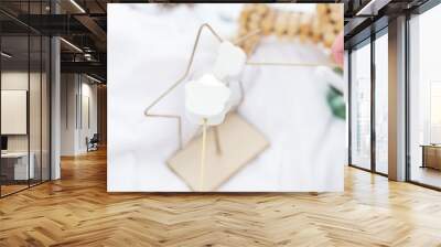 The image shows two white marshmallows skewers on stocks held by a person in a snowy outdoor setting. Wall mural