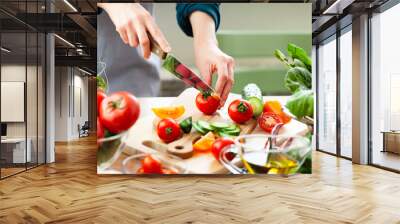 Beautiful young woman slicing red ripe tomato, preparing delicious fresh vitamin salad. Concept of clean eating, healthy food, low calories meal, dieting, self caring lifestyle. Close up Wall mural