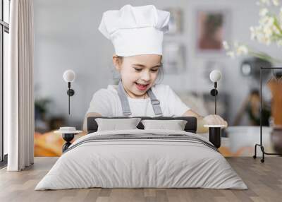 Cute little girl baking homemade sweet pie together, having fun. Home bakery, little kids in process of food preparation in the kitchen at home, helping mother, doing chores Wall mural