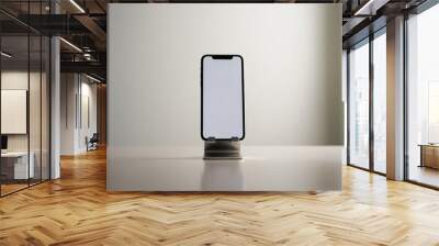 A very detailed and realistic workspace photo shows a cell phone in a stand with a blank white screen from the front view Wall mural