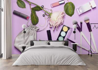 Beauty brushes with palette, beautiful pink rose, green leafs, stylish cosmetic bag of silver color on the georgios purple fon and space for text Wall mural