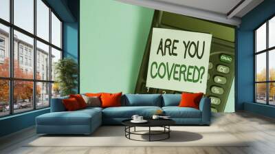 Text sign showing Are You Covered Question. Business photo showcasing asking someone or patient if he have insurance Portable electronic calculator device blank sticky note colored background Wall mural