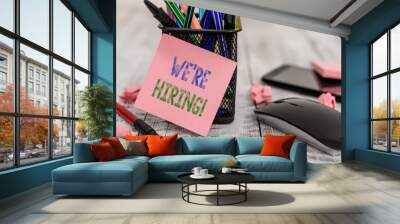 Word writing text We Re Hiring. Business photo showcasing recently employ someone or pay someone to do particular job Writing equipment and paper plus scraps with gadgets on the wooden desk Wall mural