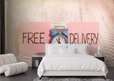 Writing note showing Free Delivery. Business concept for Shipping Package Cargo Courier Distribution Center Fragile Mini blue alarm clock standing above buffer wire between two paper Wall mural