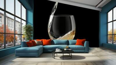 a light drink is pouring from a bottle into a glass , all on a black background Wall mural