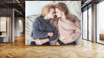 Two young women in a bright bedroom lying in bed. Sensual loving couple. Wall mural