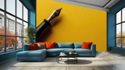 an elegant black fountain pen lays on a vibrant yellow background Wall mural