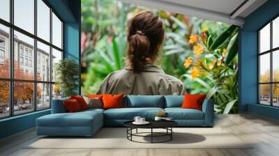 Asian woman in green jacket exploring vibrant tropical garden Wall mural