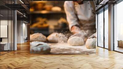 Baker kneads dough on flour-dusted surface in professional kitchen with baked goods background Wall mural